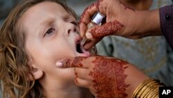 په لاهور کې روغتیايي کارکوونکې یوې ماشومې ته څاڅکي ورکوي - پخوانی انځور.