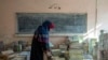An Afghan teacher collects books in a school in Kabul, Afghanistan, in December 2022.