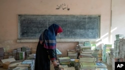 An Afghan teacher collects books in a school in Kabul, Afghanistan, in December 2022.