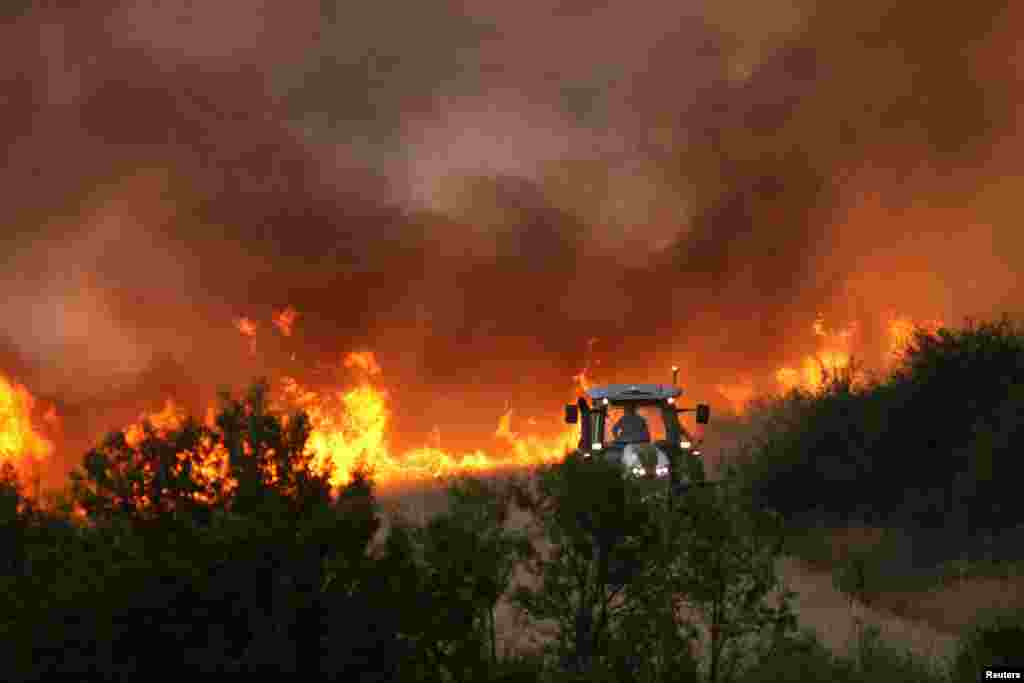 Трактор прокладывает противопожарную полосу во время лесного пожара вблизи поселения Беледие Хан, Костинброд, Болгария, 21 июля 2025 года. REUTERS/Stringer