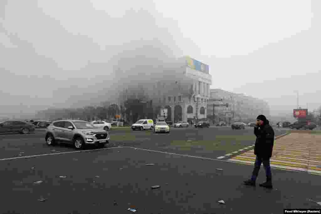 A man watches the Almaty office of Kazakhstan&#39;s state broadcaster burn on January 6.&nbsp;