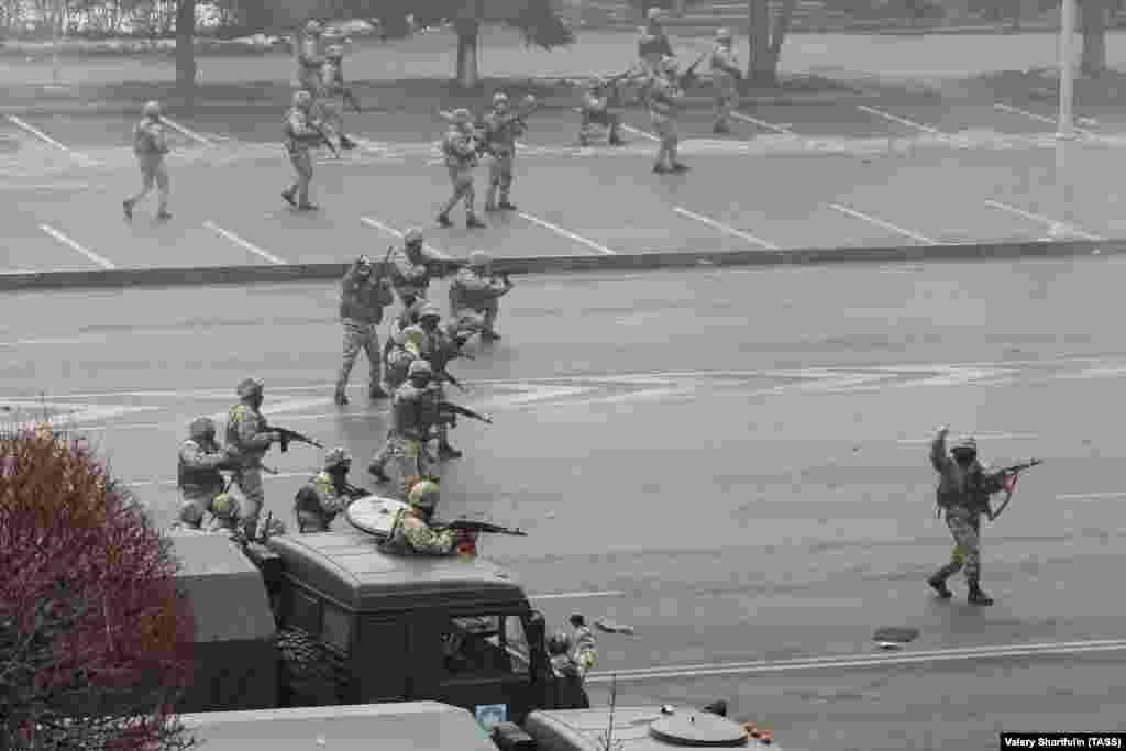 Unidentified military personnel fire their weapons in the center of Almaty on January 6. In video of this scene, the man at right appears to be signaling to stop shooting after a sustained burst of gunfire from the formation.