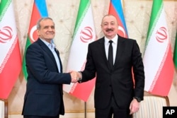 Azerbaijani President Ilham Aliyev (right) and Iranian President Masud Pezeshkian shake hands after their joint news conference following talks in Baku on April 28.
