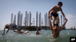 Пляж на берегу Каспийского моря в Баку на фоне нефтяных платформ, Азербайджан