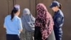 Female police officers in Osh speak to local women during a raid to enforce the niqab ban.