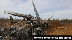 Український військовослужбовець біля залишків знищеного російського гелікоптера Мі-8. Київська область , 27 квітня 2022 року