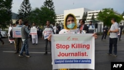 یوې خبریالې د پاکستان د پارلېمان ودانۍ مخې ته د خبریالانو وژنې د مخینوي بینر نیولی دی ـ پخوانی انځور.