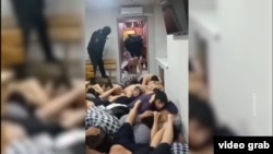 A video that has gone viral on social media shows Kyrgyz migrants being forced to crawl on the floor and lie on top of each other during a police raid in Moscow.
