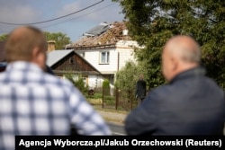 Localnici din satul Wyryki privesc o casă distrusă de o dronă, 10 septembrie 2025.