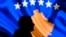 A man stands in front of a screen displaying the Kosovo flag in Pristina.