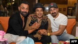 درمېندر له خپلو بچیو سني دېول (ښي لوري ته) او بابي دېول (کیڼ لوري ته) په ممبۍ کې د خپلې ۸۹مې کلیزې لمانځلو پر مهال - د ۲۰۲۴ز کال د ډېسېمبر اتمې انځور.